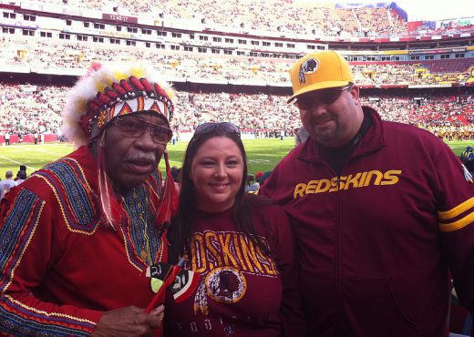 Trois personnes lors d'un match des Redskins arborant des accessoires dont certains avec des symboles traditionnels amérindiens