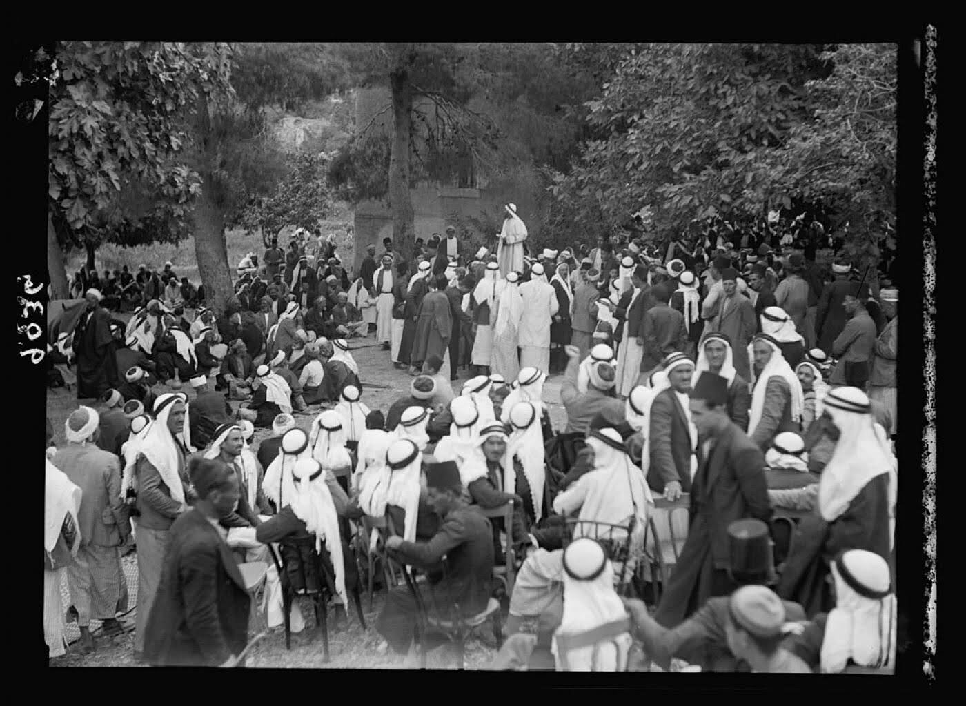 Des arabes palestiniens rassemblés à Abou Ghosh à l'ouest de Jérusalem, lors d'un piquet de grève. Foule de gens assise ou debout, portant des turbans blancs et des kufi autour d'un orateur dans un jardin.